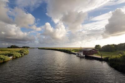 På billedet ses Ringkøbing Fjord. Til venstre i billedet er der et lille hus med en dertilhørende båd