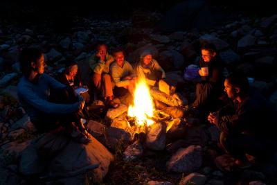På billedet ses en forsamling af mennesker, der sidder samlet om en bål i skoven